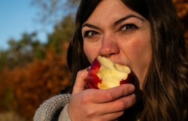 woman in gray sweater holding sliced of apple